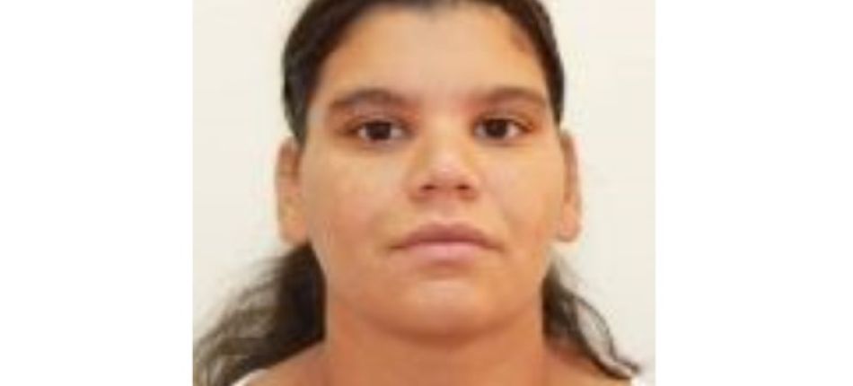 Portrait of a young woman with dark hair tied back, wearing a white top, neutral expression against a light background.