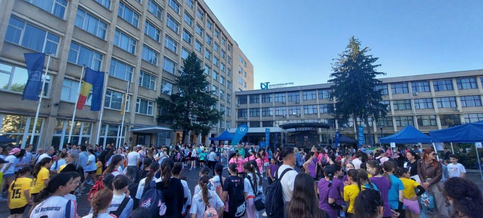Crowd of students gathered in a university courtyard for a campus event, with blue tents and flags visible.
