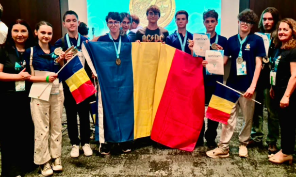 Group of young competitors holding Romanian and Ukrainian flags, wearing medals and certificates at an awards ceremony on stage.