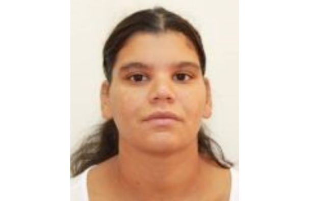 Portrait of a young woman with dark hair tied back, wearing a white top, neutral expression against a light background.