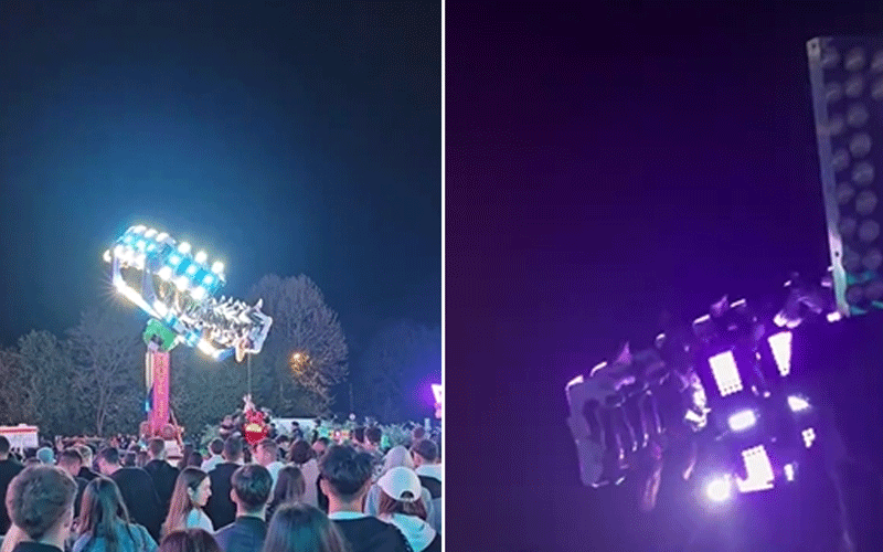 Nighttime amusement ride with bright blue lights spinning above a crowd of riders at a fairground.