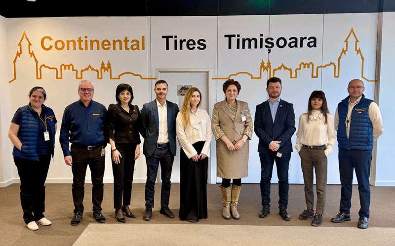cciat-conti2 - Sursa de Vest Nine professionals posing for a group photo in front of a wall that reads 'Continental Tires Timisoara' with an orange skyline graphic.