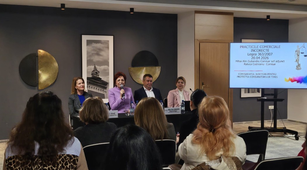 Panel discussion with four speakers seated at a long table, audience watching, and a slide projected on the right in Romanian.