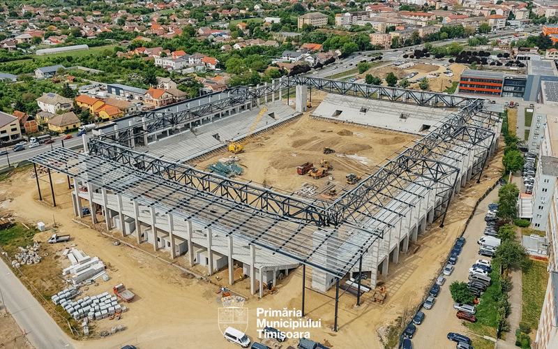 Aerial view of a large stadium under construction with steel frame and concrete walls in a residential area, Timisoara.