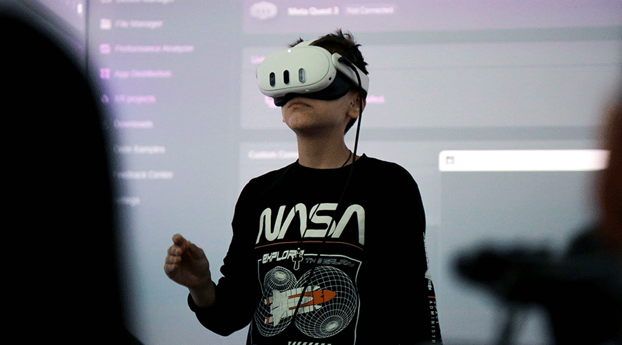 Person wearing a white VR headset and a NASA-themed shirt, standing in front of a projected screen during a demo.