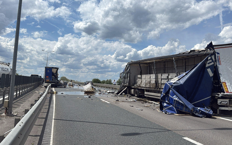 accident-tiruri-a1 - Sursa de Vest Highway crash scene with two semi-trailers, scattered debris, and a blue tarp covering cargo on the right, under a cloudy sky.