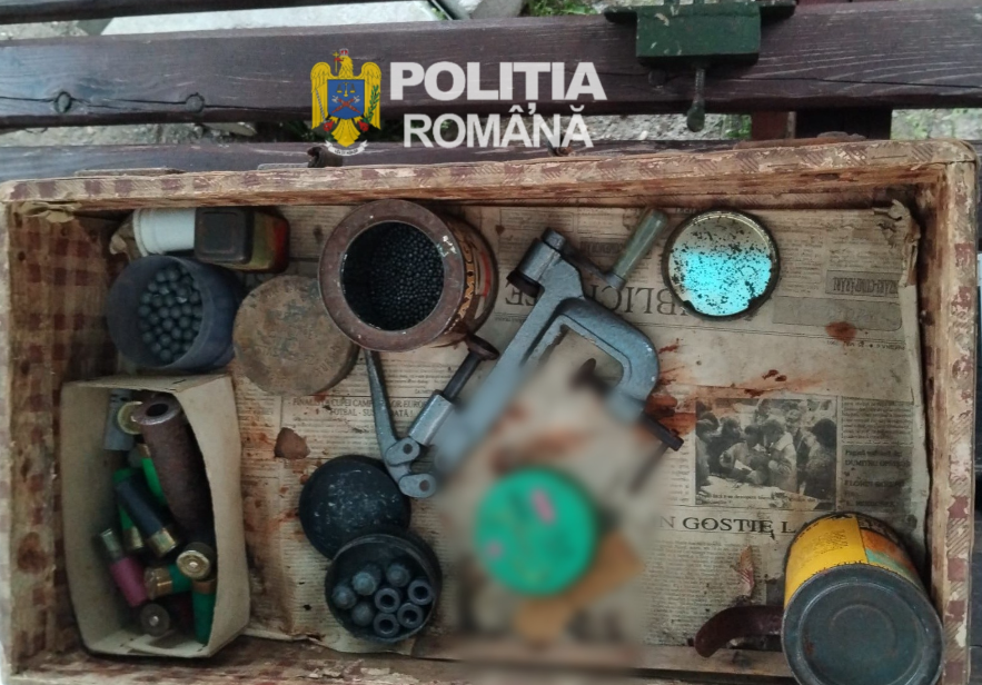 Seized cache of weapons and ammunition in a wooden tray, with the Politia Romana logo visible above.