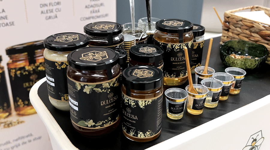 Jars of Dulcesa spread and honey on a black-topped display with tasting cups and spoons side by side.