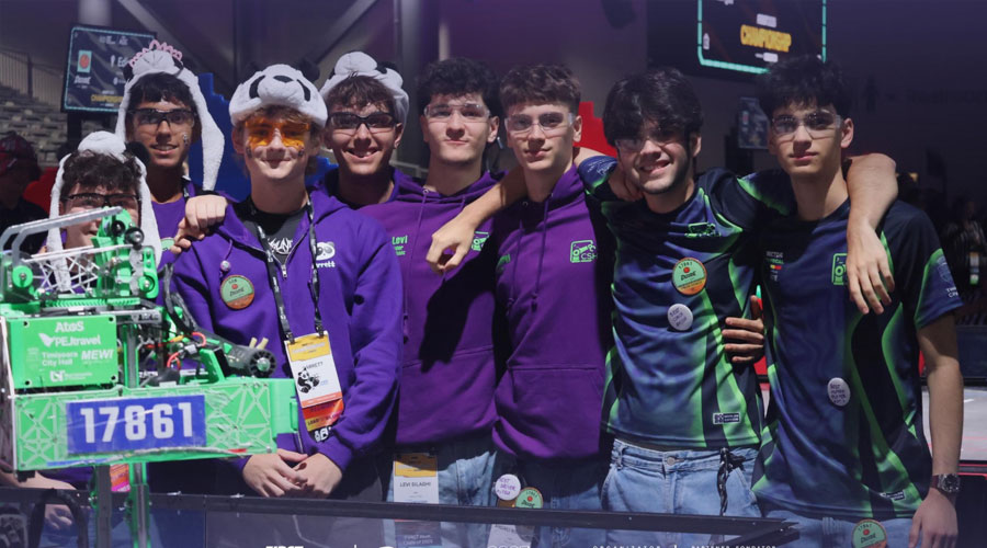 Seven students in purple team hoodies pose with a green robotics robot at a competition site.