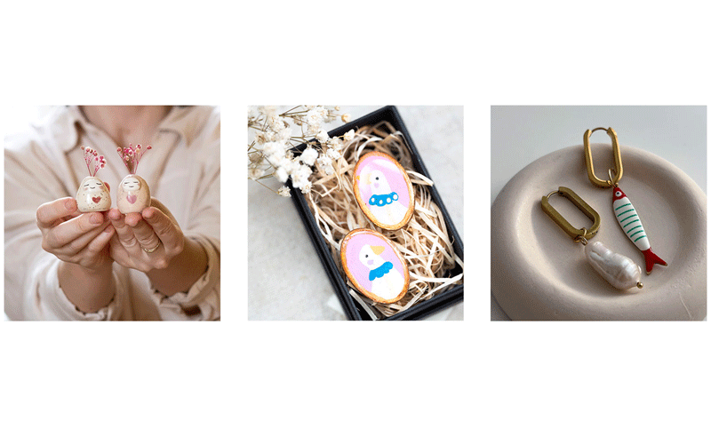 Two tiny hand-painted ceramic dolls with pink floral headdresses being held between fingers.