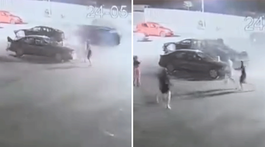 Security camera frames of a collision: a dark car crashes into another vehicle while bystanders watch, producing smoke and dust at a parking area or gas station.