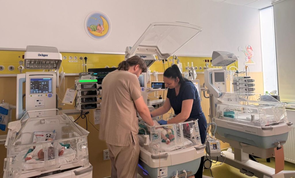 neonatologie 2 - Sursa de Vest Neonatal intensive care unit: two healthcare workers attend preemie twins in clear incubators filled with tubes and monitors.