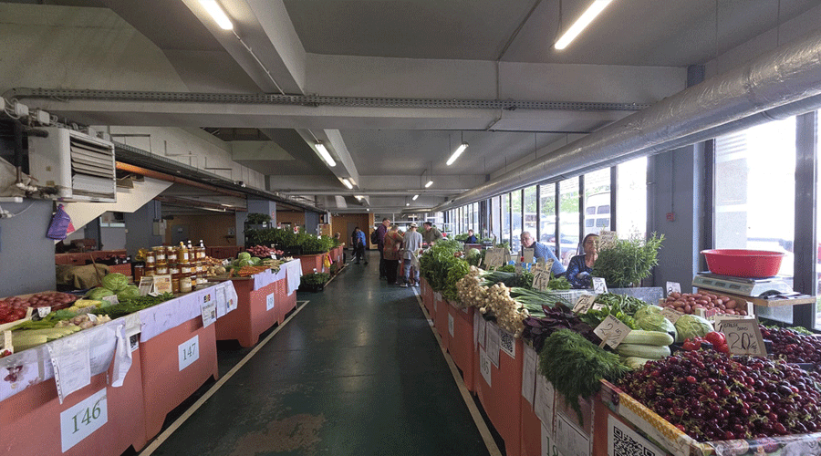 piata-iosefin-04 - Sursa de Vest Indoor farmers market with long rows of produce stalls, shoppers browsing fresh vegetables and fruit under fluorescent lights.