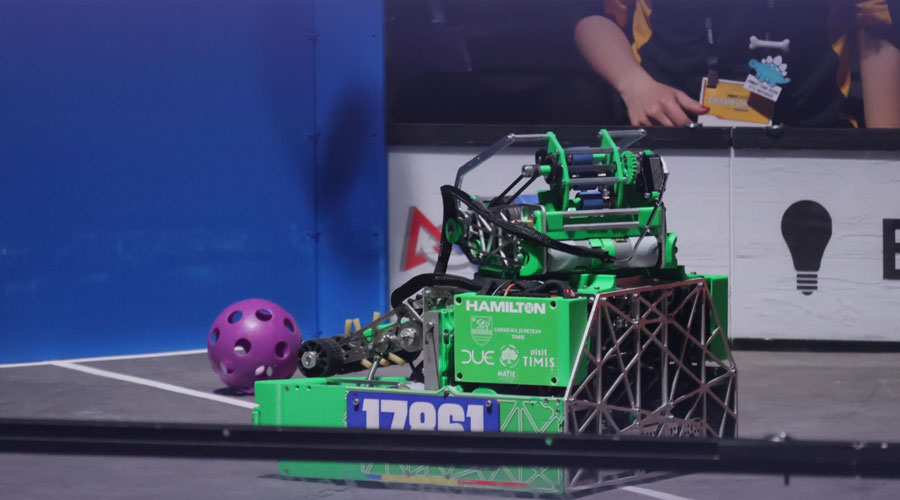 Green competition robot with a purple scored ball on a field, displaying number 17861 and drill-like gripper components.
