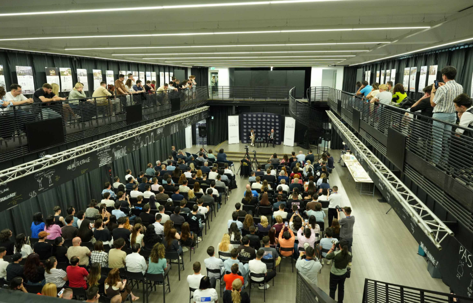 traian basescu2 - Sursa de Vest Wide view of a conference: a large audience seated on the ground floor and people on the upper balcony, facing a panel on stage.