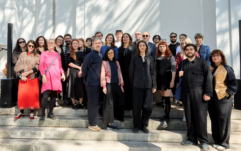 uvt-viena - Sursa de Vest Large diverse group of men and women standing on outdoor steps in front of a modern building, posing for a group photo.