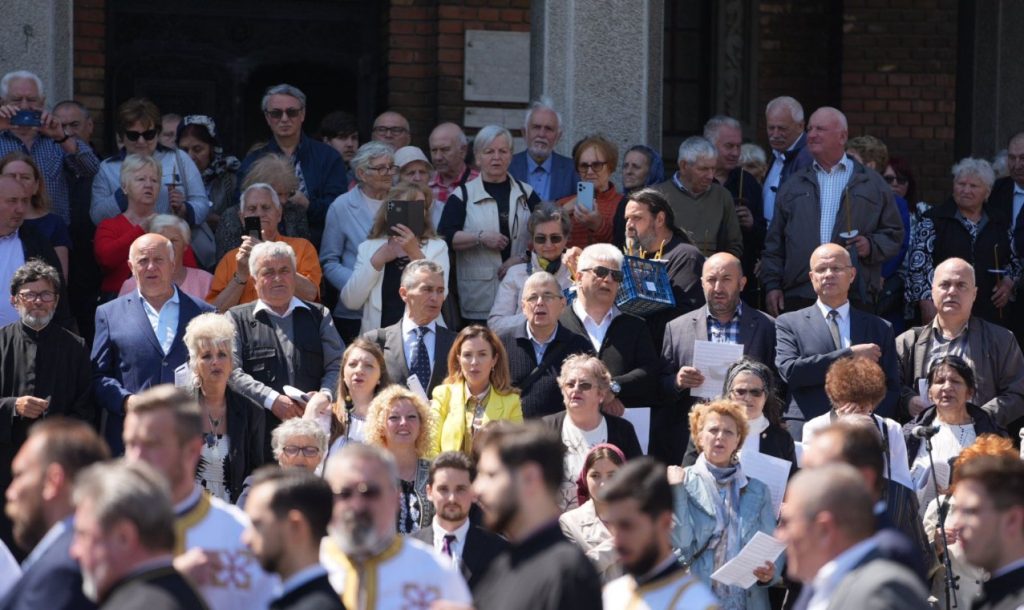 ziua eroilor 5 - Sursa de Vest Large crowd of mainly older adults gathered outside a brick building, many holding papers or phones.