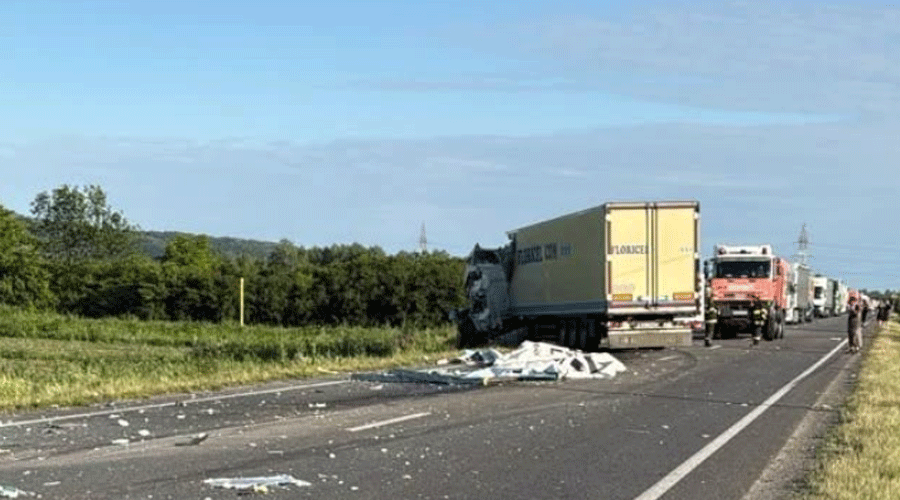 accident-jupa - Sursa de Vest Highway crash scene with a damaged semi-truck and debris scattered across the road, lined up trucks behind it.