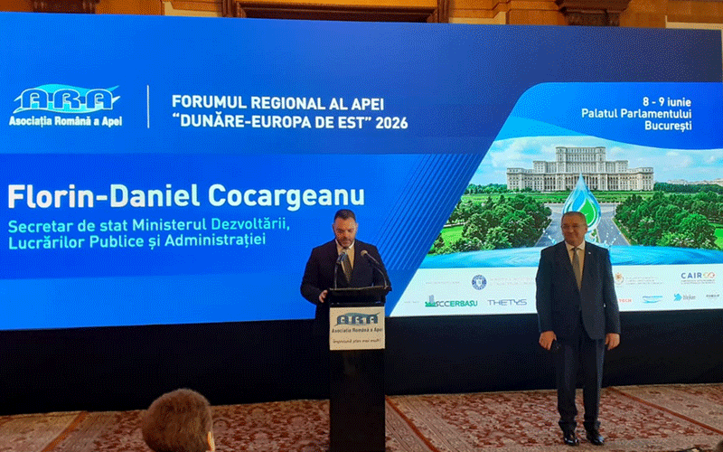 aquatim-forum - Sursa de Vest Florin-Daniel Cocargeanu at a podium during a regional forum, with a large blue banner behind him listing the event name and his title as Secretary of State for Development, Public Works and Administration (Romania).
