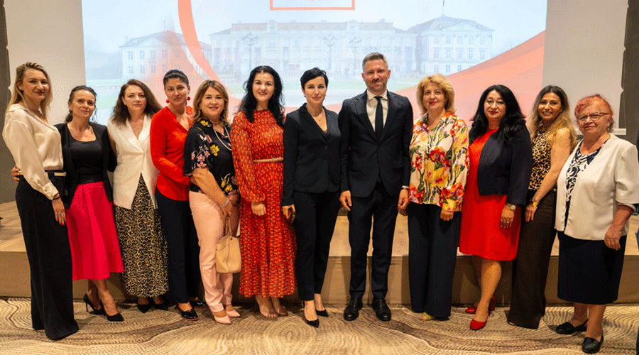 Group of about 14 professionals posing together on a stage at a formal event, dressed in business and smart casual attire.