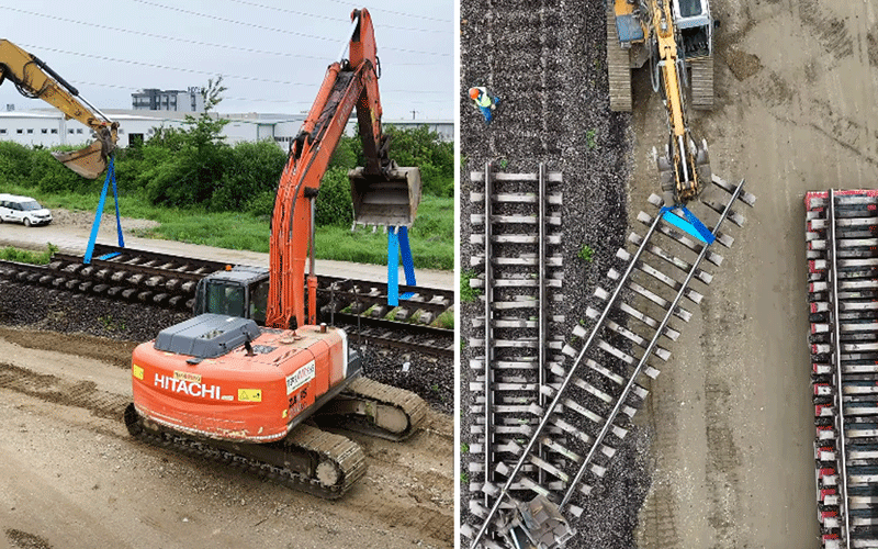 Orange Hitachi excavator on a muddy construction site lifting blue straps near a railroad line.