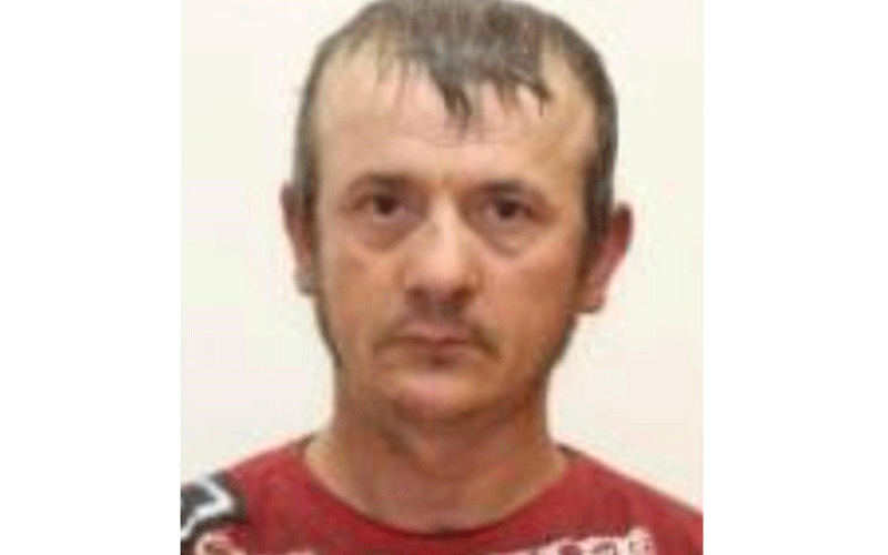 Head-and-shoulders photo of a man with short dark hair and a red shirt, looking straight at the camera with a neutral expression