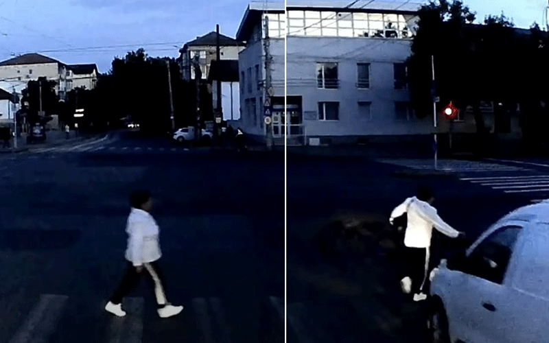 Person crossing a crosswalk on the left; another person near a white car on the right at an urban intersection.
