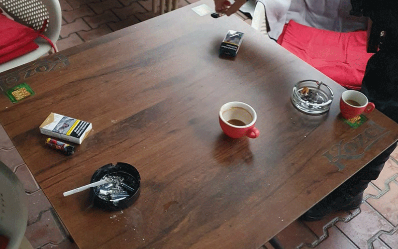 fumatori - Sursa de Vest Top-down view of a wooden table with three red coffee cups, an ashtray, a cigarette pack, lighter, and a cigarette butt.