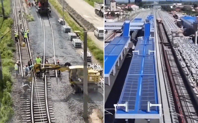 Railway construction with workers and a yellow excavator laying ballast on tracks.