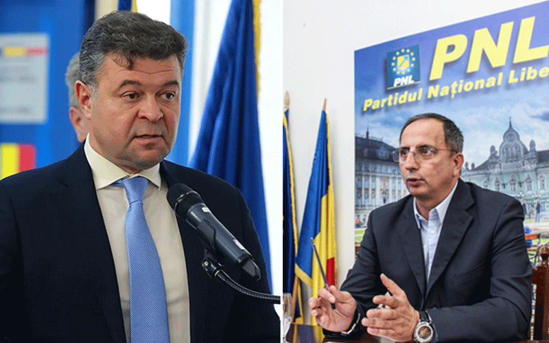 Two men in suits at a political event: one speaking into a microphone, the other seated with a PNL banner behind him.
