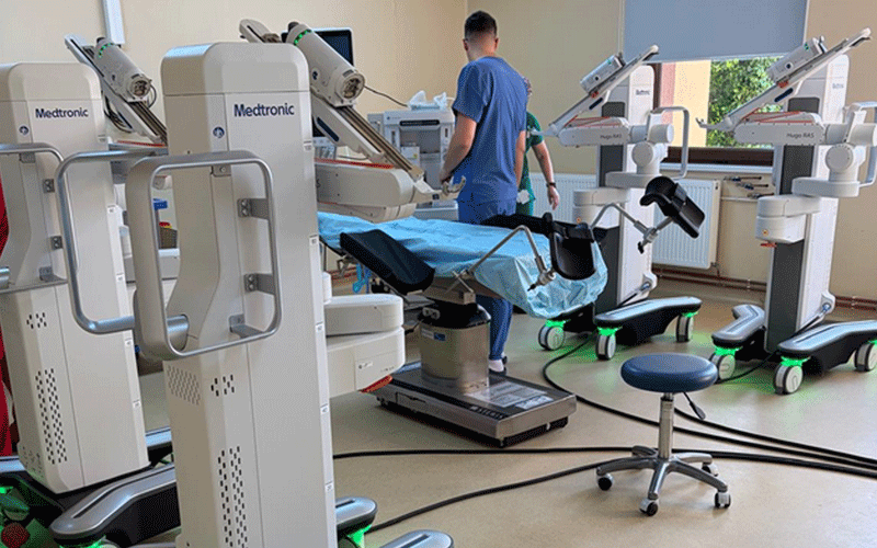 Operatory room with multiple robotic surgical arms and a patient on the operating table, medical staff in scrubs nearby