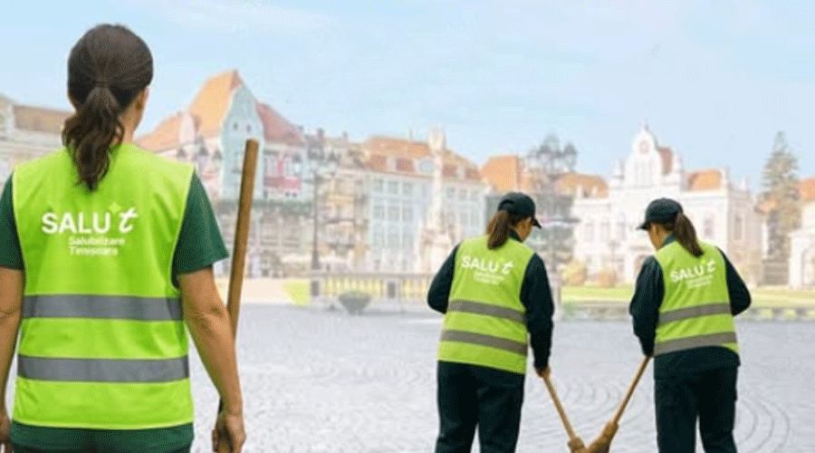 Three municipal street cleaners wearing neon vests sweeping a cobblestone plaza with colorful historic buildings in the background.
