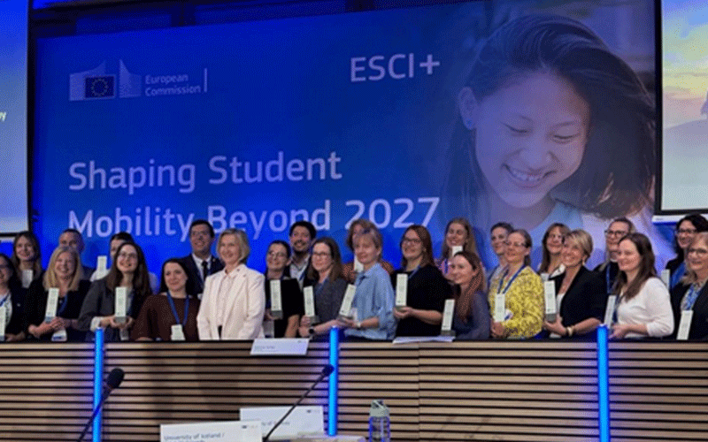 Group photo of diverse professionals standing behind a conference desk, each holding a certificate, at the Shaping Student Mobility Beyond 2027 event (ESCI+).