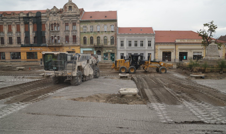 cartier fabric3 - Sursa de Vest Construction site in a town square with vintage storefronts and heavy machinery leveling dirt in the street behind them, under renovation.