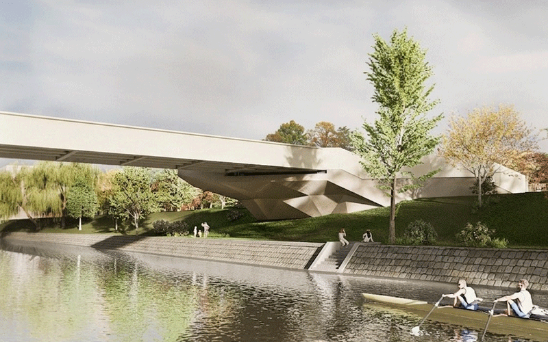 pasarela-indragostitilor-2 - Sursa de Vest Modern concrete bridge over a calm river with a grassy embankment; people walk along the path and a two-person rowing shell glides nearby.