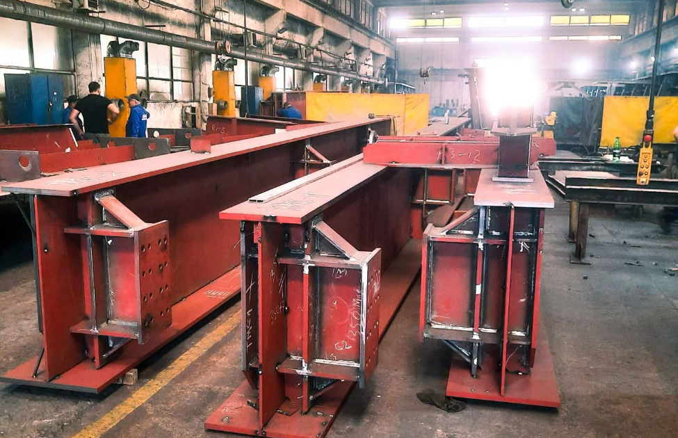 piese pod muncii - Sursa de Vest Industrial workshop with large red steel beams and welded frames awaiting assembly in a fabrication shop
