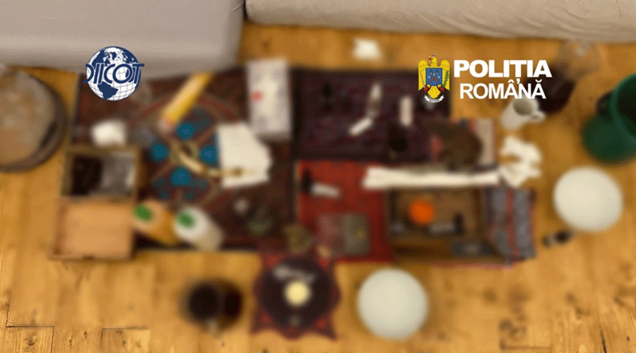 Overhead view of a cluttered wooden floor with a small work area of assorted items; logos of Interpol (left) and Polícia Română (right) at the top.
