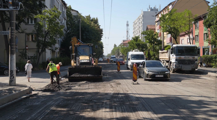 construction workers and an excavator repair a road with traffic cones on a city street