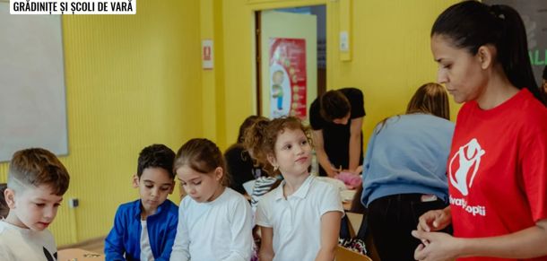 Children participate in a summer camp activity in a yellow classroom; a staff member in a red shirt supervises.