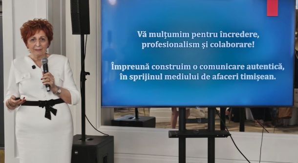 Woman in a white dress speaks into a handheld microphone beside a large screen displaying Romanian text about gratitude, professionalism and collaboration: 'Vă mulțumim pentru încredere, profesionalism și colaborare! Împreună construim o comunicare autentică, în sprijinul mediului de afaceri timișean.'