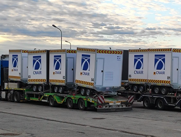 Row of CN AIR cargo containers on a multi-axle transport trailer at an airport tarmac.