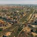 Aerial view of a town with multiple rail lines crossing a central area, bordered by residential blocks and roads.