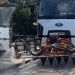 Front view of a white Ford street-cleaning truck spraying water through a bar with multiple nozzles onto the street surface.