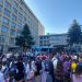 Crowd of students gathered in a university courtyard for a campus event, with blue tents and flags visible.