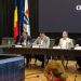 Five men sit at a long panel table in a council chamber, with flags behind and a large screen displaying 'CONSILIUL JUD TIMIȘ'.