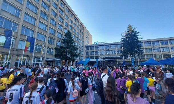 Crowd of students gathered in a university courtyard for a campus event, with blue tents and flags visible.