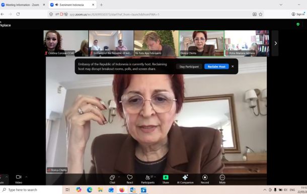 Video conference screenshot: main speaker Florica Chirita wearing glasses and a brown blazer, with participant thumbnails along the top edge.