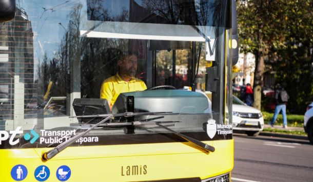 Public transit bus front view with a driver in a yellow shirt; Timisoara branding and accessibility icons on the bumper.
