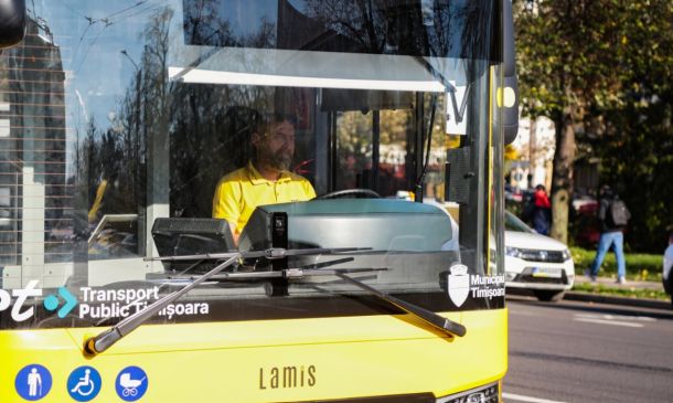 Public transit bus front view with a driver in a yellow shirt; Timisoara branding and accessibility icons on the bumper.