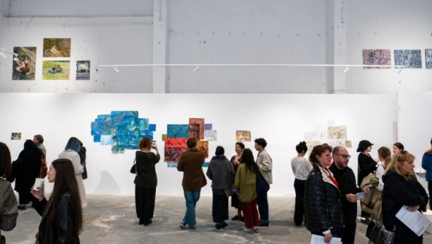 Group of people viewing abstract blue collage on a white gallery wall in a spacious room